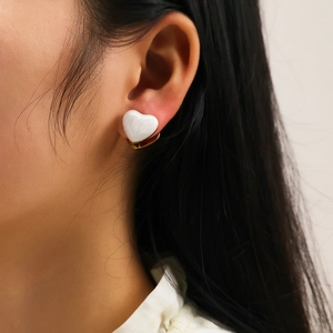 Boucles d'oreilles cœur élégantes en marbre et plaqué or portées par un mannequin