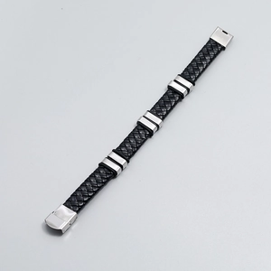 Détail du bracelet en cuir tressé noir avec anneaux métalliques et fermoir pliant