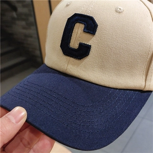 Close-up of the large navy blue embroidered letter C on a beige cotton twill baseball cap