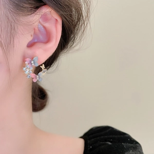 Close-up of butterfly stud earring with pink-blue gradient resin and sparkling rhinestones
