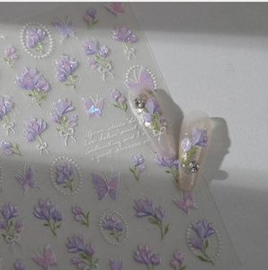 Détails macro de stickers ongles 3D avec tulipes violettes et papillons sur fond blanc