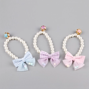 Detailed view of pearl pet collars with checkered bows and golden flower bells for small dogs