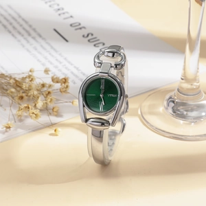 Detail of horseshoe-shaped silver watch with emerald green dial and Roman numerals