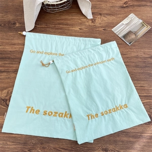 Detail of mint green drawstring organizer bags with yellow embroidery on wooden table