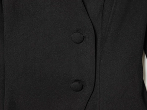 Close-up of black blazer fabric showing fine twill texture and matching fabric buttons