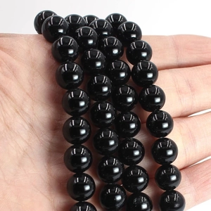 Detailed view of polished black agate round beads held in hand for DIY jewelry making