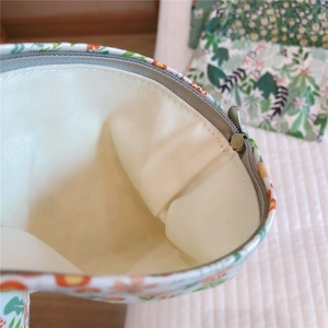 Detail shot showing the beige cotton lining and floral green fabric of the mini pouch