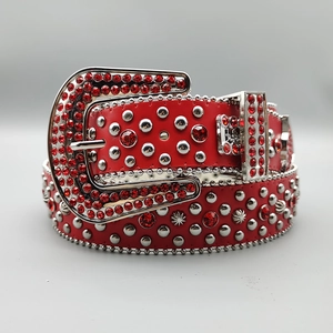 Macro shot of red leather belt featuring silver studs and red rhinestones with large buckle