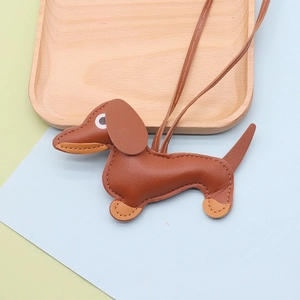 Close-up of brown dachshund leather keychain charm with contrast stitching on wooden tray