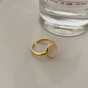 Close-up of minimalist gold open ring featuring a round opal stone and smooth metallic finish