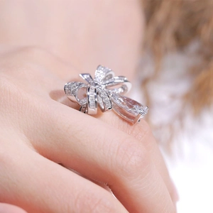Macro detail of silver bow ring featuring pear-cut center stone and pave zircon setting