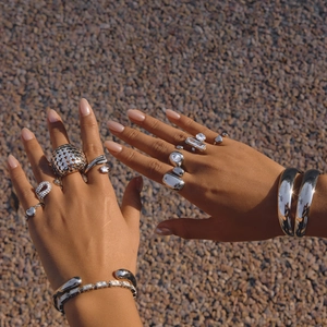 Outdoor shot showing silver stacked hollow rings and bracelets with zircon stones