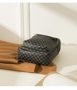 Detailed view of dark grey patterned chest bag on brown fabric with natural sunlight