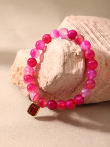 Macro shot of natural agate beaded bracelet with red rectangular gemstone pendant