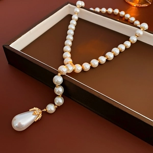 Detail of waterdrop pearl necklace with gold floral clasp inside a luxury gift box
