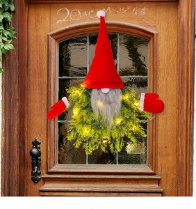 Illuminated Christmas gnome wreath with red hat and LED lights on a vintage wooden door