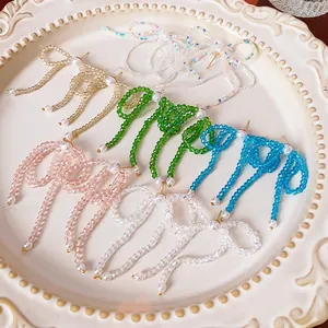 Elegant bow fringe earrings with colorful crystal beads and pearls on a vintage plate