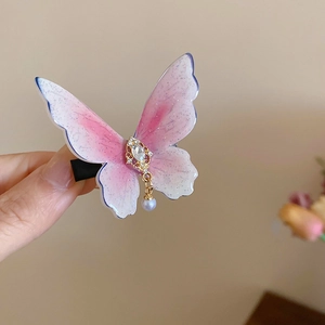 Détail de la pince à cheveux papillon dégradé rose avec strass et perle pendante