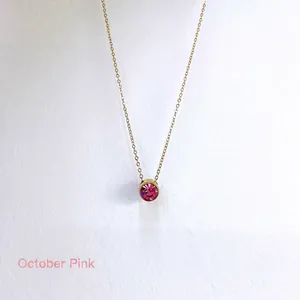 Detail of October birthstone necklace with pink round zircon pendant in gold plating