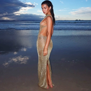 Detail of a golden backless halter dress featuring a sexy side slit against a sunset beach
