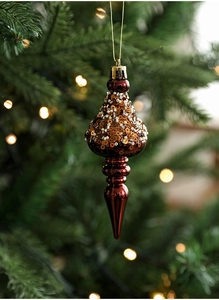 Close-up of red-brown teardrop Christmas ornament with sequins on a festive tree