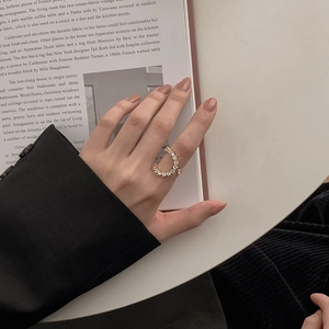 Elegant gold-tone ring with crystals worn on hand over a magazine on a white table