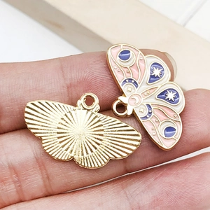 Close-up of golden butterfly pendants with colorful enamel details for DIY jewelry