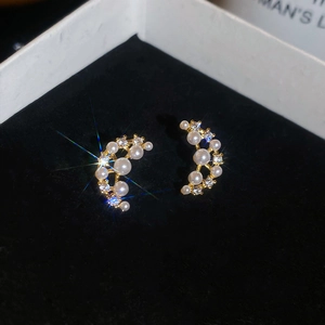 Detailed close-up of crescent moon earrings with white pearls and sparkling cubic zirconia