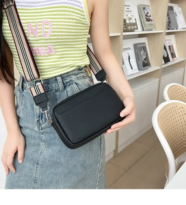 Close-up of black lychee grain PU leather bag with striped wide shoulder strap detail