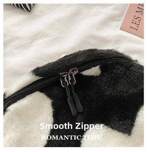 Detailed close-up of the smooth double zipper on this black and white cow print plush bag