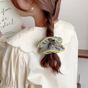 Detail of blue floral scrunchie with yellow trim worn by model in an elegant back view