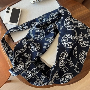 Detail of navy canvas tote with white cat embroidery on a wooden table with accessories