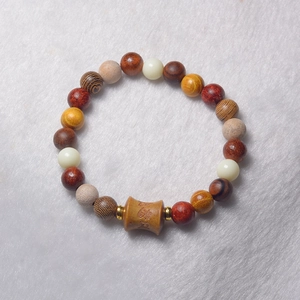 Macro shot of Buddhist prayer beads bracelet with carved wood barrel and golden spacers