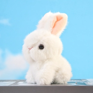 Side view of soft white plush rabbit pendant against a bright blue sky background