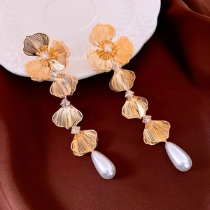 Dettaglio degli orecchini a fiore dorati con zirconi e nappe di perle eleganti