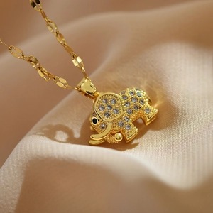 Macro detail of gold elephant pendant with white zircon crystals on silk background