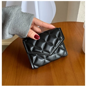 Close-up of a small black quilted leather folding wallet held in hand for size display