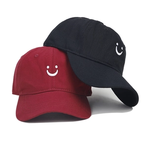 Detail of smile face embroidery on cotton twill baseball caps in burgundy and black