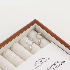 Macro shot of S925 silver conch hoop earrings with crystals in a wooden jewelry box