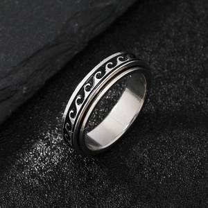 Rotating stainless steel spinner ring with black wave pattern on dark stone background