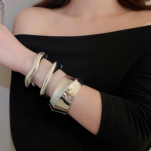 Close-up of three layered silver polished metal bangles with minimalist wavy design