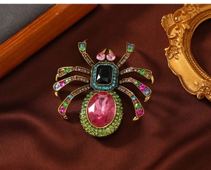 Macro detail of vintage gold spider brooch with pink crystal and colorful rhinestones