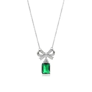 Detailed view of silver bow necklace with large emerald-cut green gemstone pendant