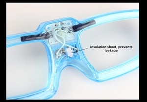 Macro view of LED glasses showing circuit board and white safety insulation tab