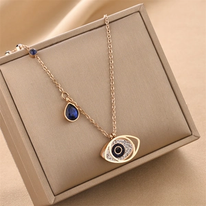 Golden Evil Eye necklace with blue teardrop crystal on premium jewelry display case