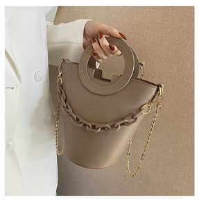 Detail of khaki bucket bag showing round ring handle and decorative thick link chain texture