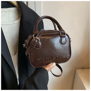 Detail of vintage oil wax leather mini handbag with logo embossing and silver hardware