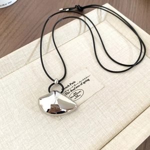 Detailed view of irregular silver metal pendant on black adjustable cord necklace