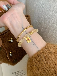 Gros plan d'un bracelet en perles dorées avec pendentif zircon et gemme rouge