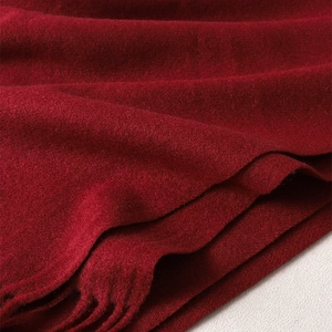 Close-up of deep red cashmere-feel scarf texture with soft fringe edge detail